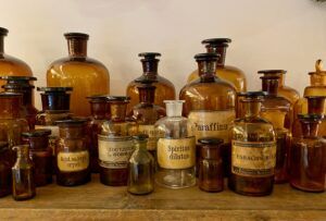 Groep vintage apothekersflessen met amberkleurig glas op een houten plank.